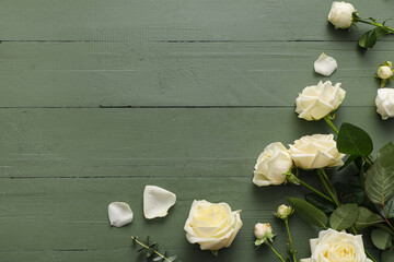 Naklejka premium Beautiful white roses and eucalyptus branch on green wooden background