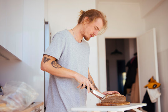 Individual slicing bread on countertop with peaceful planning attitude - Powered by Adobe