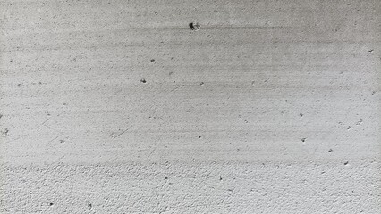 Texture of a rough gray cement wall surface with small holes and subtle patterns, ideal for backgrounds, construction themes, and industrial design.