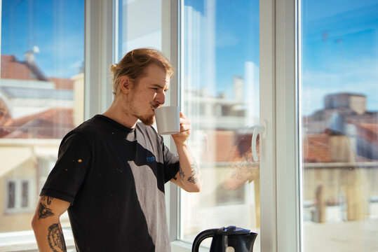 Person relaxing by window with coffee and city backdrop