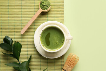 Cup of fresh matcha tea with scoop, powder and chasen on green background