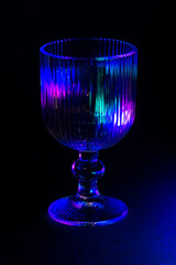 Colorful Lit Glass Goblet with Intricate Details in Dark Ambiance