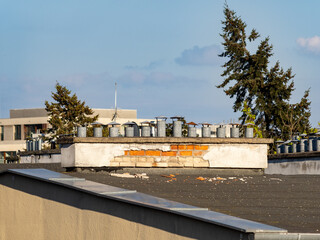 Fototapeta premium Rooftop Chimneys and Vent Pipes on Flat Urban Roof Under Clear Sky