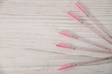 Eyelash brushes arranged on a wooden surface showcasing beauty tools for eyebrow artistry