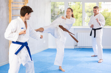 Obraz premium Man and woman train to perform basic defensive installations and attacking actions during combat techniques classes. Young male coach comments and corrects mistakes of students