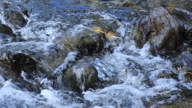 Fast-flowing river water and boulders. Jamor River - Rio Jamor, Oeiras, Portugal.	