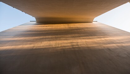 Looking Up From Underneath A Concrete Bridge With Golden Sunlight Casting Long Shadows On A Clear Day