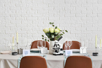 Elegant table setting for Nobel prize day with microscope, flowers and candles in dining room