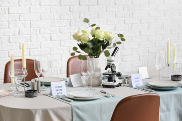 Elegant table setting for Nobel prize day with microscope, flowers and candles in dining room
