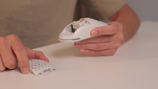 Mouse shell replacement, Closeup of fingers attaching top cover to wireless gaming mouse, Minimalist workspace with focus on precise assembly of gaming mouse components