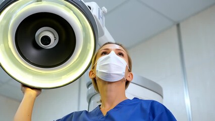 Female Healthcare Worker in Scrubs Adjusting Medical Equipment for Patient Care