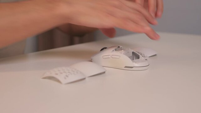 Mouse shell replacement, Closeup of fingers attaching top cover to wireless gaming mouse, Minimalist workspace with focus on precise assembly of gaming mouse components