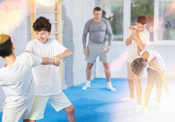 Obraz premium Sporty boys practices self-defence moves in pairs in modern sporty gym