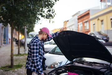 Youthful Caucasian individual working on car engine at evening