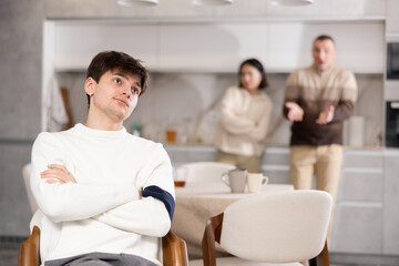 Young man relatives are unhappy with his behavior and scold him in the home kitchen