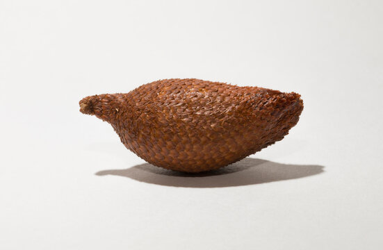 Salak (Salacca zalacca) is a species of palm tree (family Arecaceae), snake fruit or snakeskin fruit due. One fruit on a white background.