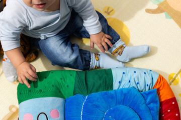 Toddler playing on colorful mat with plush toy