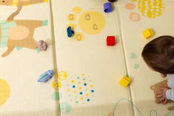 Baby playing with colorful toys on floor mat