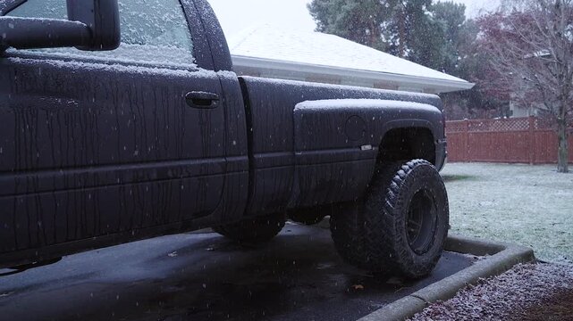 Light snow falling on a matte black pick-up truck