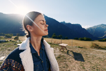 Fototapeta premium Woman profile with eyes closed in sun and mountains, outdoor nature portrait capturing relaxation and travel mood, peaceful breathing, scenic valley and warm light on face.