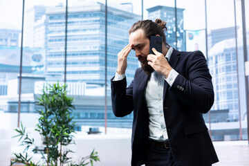 Corporate boss discusses transactional details with a financial broker on phone call, using his mobile phone to hear updates on stock market forecasts. Handles high pressure situations.