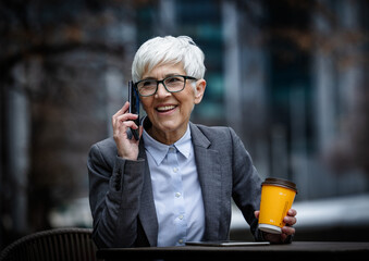 Business woman talking on phone while holding coffee cup