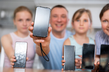 Happy family of four showing the screens of their phones