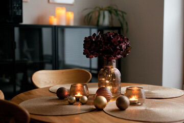 Cozy home atmosphere. Christmas lights and decoration on wooden table in nordic interior.