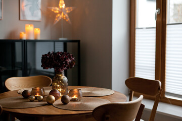 Cozy home atmosphere. Christmas lights and decoration on wooden table in nordic interior.