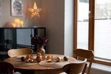 Cozy home atmosphere. Christmas lights and decoration on wooden table in nordic interior.