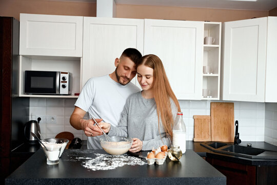Couple preparing dough in a kitchen during daylight while engaging in cooking conversation and enjoying the process together - Powered by Adobe