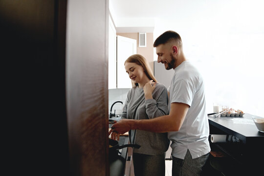 People cooking together in a modern kitchen during morning hours, showing teamwork and shared enjoyment in the culinary process