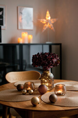 Cozy home atmosphere. Christmas lights and decoration on wooden table in nordic interior.
