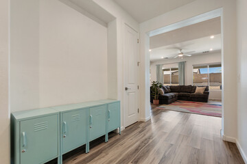 A hallway leading to a living room with hardwood floors and lockers