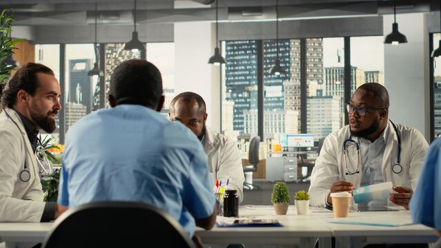 Group of doctors participating in a healthcare team meeting to review patient care. The discussion focuses on treatment planning and advancement in modern medical clinic.