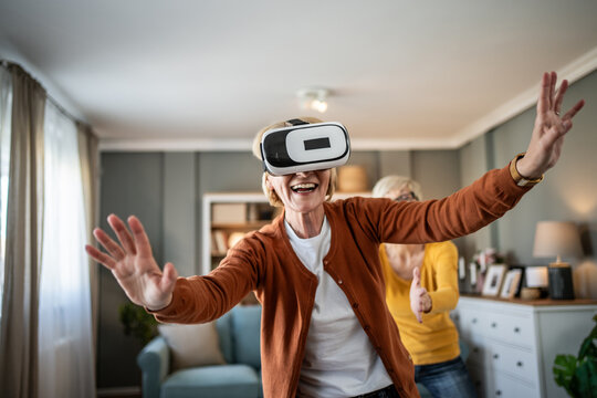 Senior woman experiencing virtual reality technology at home - Powered by Adobe
