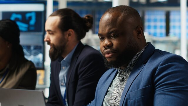 Factory manager developing lucrative business model using laptop, expanding production. Man works on integrating automation technology in industrial plant, looking at equipment on notebook, camera B