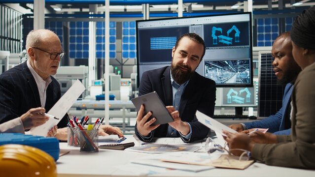 Business executives meet with investors to discuss the integration of automation technology in solar panel production processes, looking over paperwork and schematics, camera A - Powered by Adobe