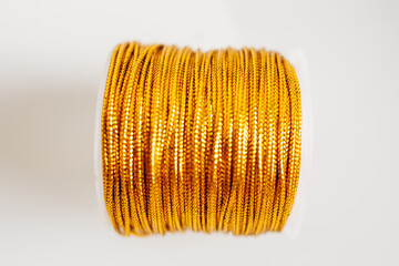Gold thread spool close-up on white background