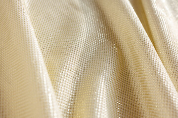 gold metallic stretch fabric with shimmering textured surface and flowing folds in soft light
