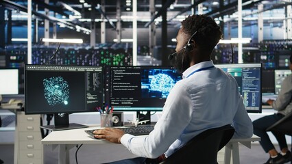 Data center employee talking in headset mic, coordinating technicians setting up hardware for artificial intelligence deployment. Server room worker engages in remote call with engineers, camera A