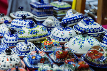 Bunzlaue ceramics and polish pottery with colorful traditional patterns displayed on a market stall table, showcasing handcrafted artisan tableware.