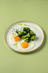 Two perfectly cooked sunny-side-up eggs sit beside vibrant green broccoli drizzled with olive oil, creating a fresh and healthy breakfast scene