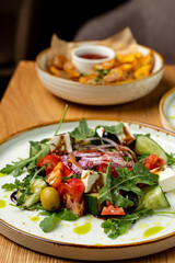 Crisp lettuce, juicy tomatoes, and tangy olives combine in a colorful Mediterranean salad adorned with creamy feta. Enjoy this delightful dish in a warm, inviting atmosphere