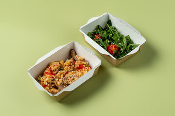 Delicious meal boxes feature a savory quinoa dish with vegetables alongside fresh salad topped with cherry tomatoes. Perfect for a healthy lunch option that looks appealing