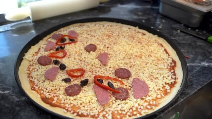 Close up of adding red paprika pieces to fresh pizza dough
