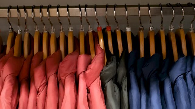 Thin winter multi-colored jackets on hangers, side view.