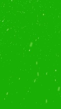 Realistic snow falls across the screen on green screen background, falling snowflake particle effects for christmas holiday celebration, overlay natural winter storm weather vertical backdrop