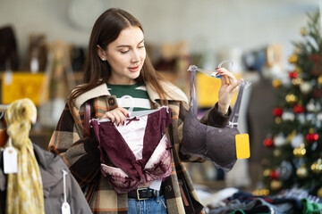Young woman buyer choosing lace lingerie in clothing store decorated for christmas