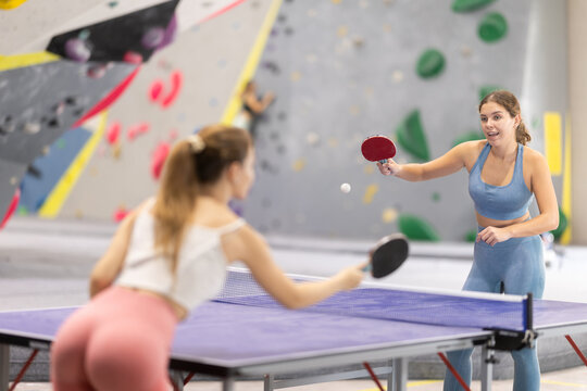 Girl athletes train and play table tennis ping pong, practice reaction speed and impact strength. Player hits ball with racket, makes pass..